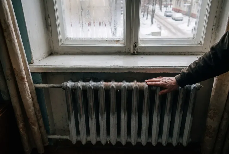 Main posée sur un radiateur de logement collectif en hiver